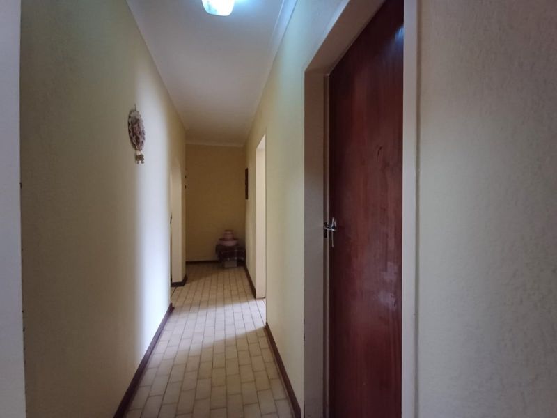 A functional residential hallway featuring tiled flooring and wooden door access to adjacent rooms.