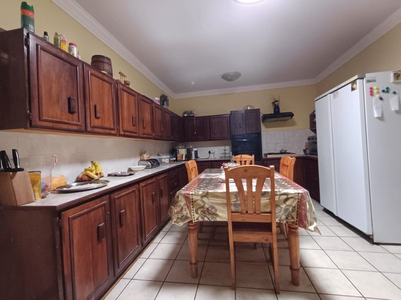 A functional kitchen featuring extensive wooden cabinetry, tiled flooring, built-in oven, and extractor fan, offering a traditional layout with ample storage space.