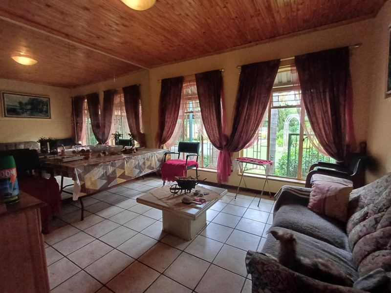 Spacious living area featuring tiled flooring and a warm timber tongue and groove ceiling with large windows providing natural light.