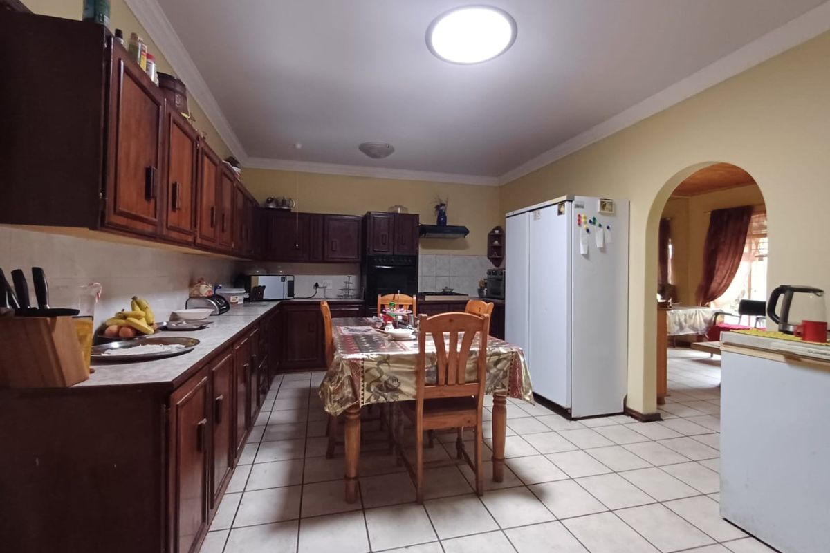 Spacious kitchen featuring traditional wooden cabinetry, tiled flooring, and an open archway leading to the adjacent living area.