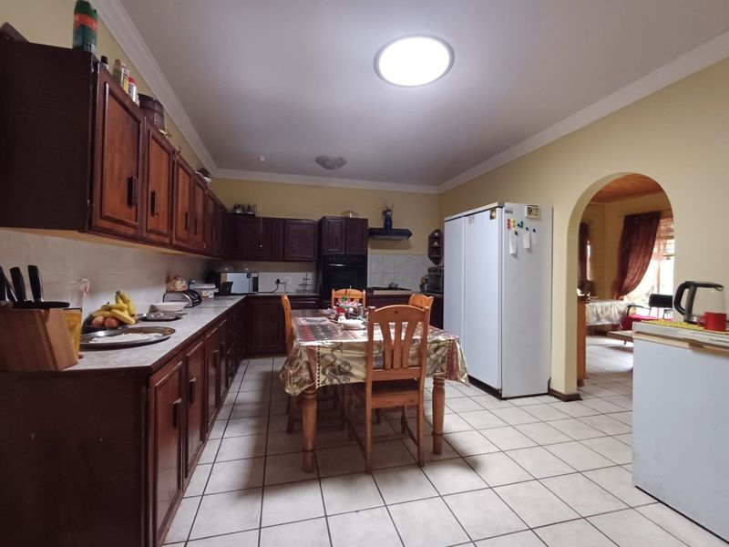 Spacious kitchen featuring traditional wooden cabinetry, tiled flooring, and an open archway leading to the adjacent living area.