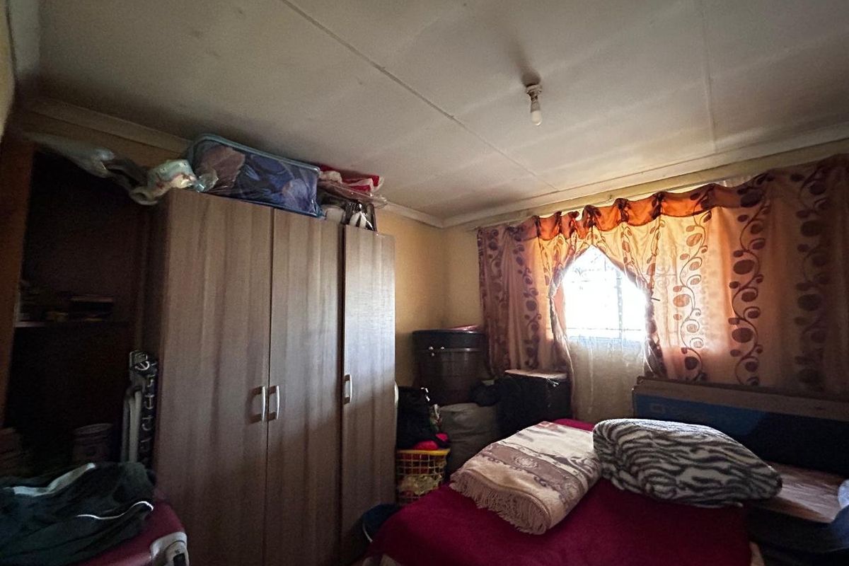 A bedroom featuring a built-in wardrobe and a window, requiring cosmetic updates to improve the overall condition of the finishes.