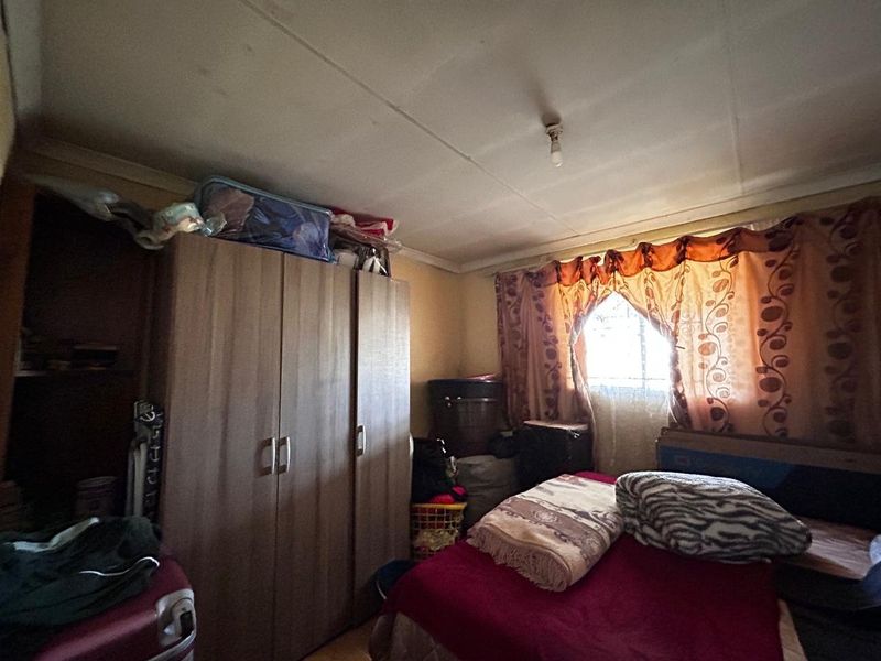 A bedroom featuring a built-in wardrobe and a window, requiring cosmetic updates to improve the overall condition of the finishes.