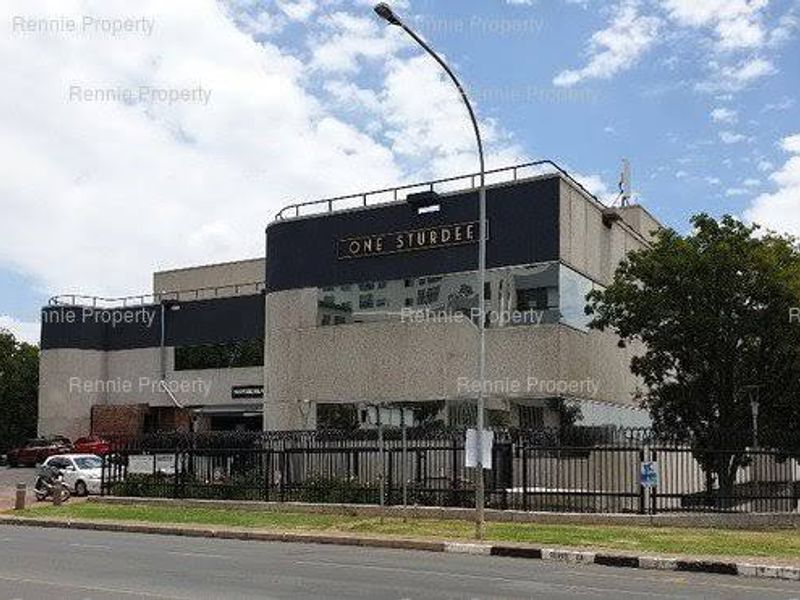 Exterior view of a commercial office building featuring a modern facade, secure perimeter fencing, and prominent street-level signage.