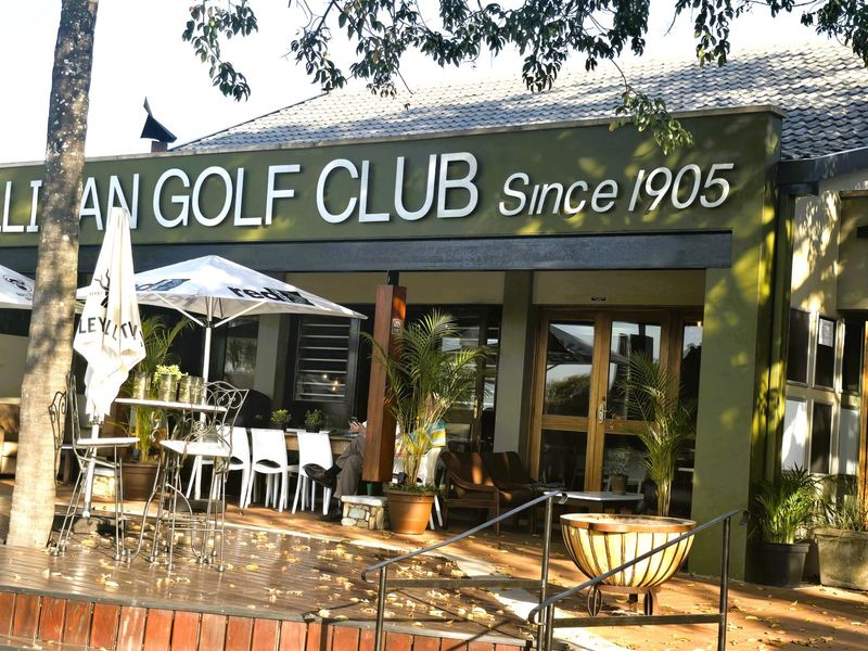 Exterior view of the Cullinan Golf Club clubhouse featuring a timber deck, outdoor seating area, and prominent signage.