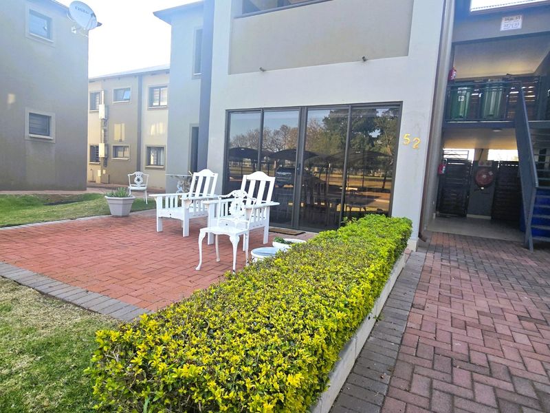 A rear exterior view of the property featuring a brick-paved patio area, sliding glass doors, and access to an external staircase.