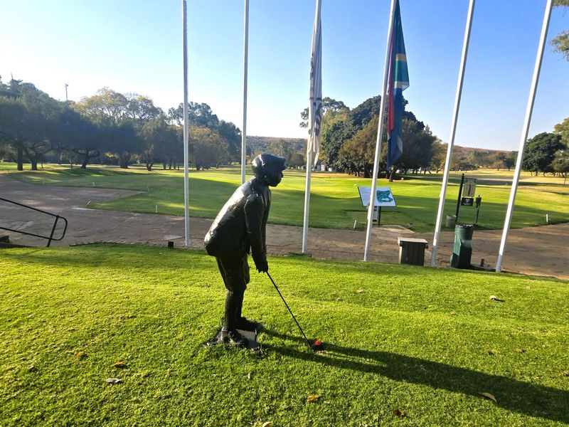 A scenic view overlooking a well-maintained golf course area featuring landscaped lawns, paved pathways, and multiple flagpoles.