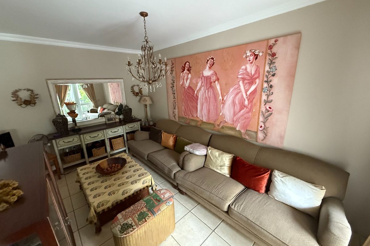 A comfortable living room featuring ceramic tile flooring, decorative cove cornicing, and a classic crystal chandelier, providing a warm and inviting atmosphere.