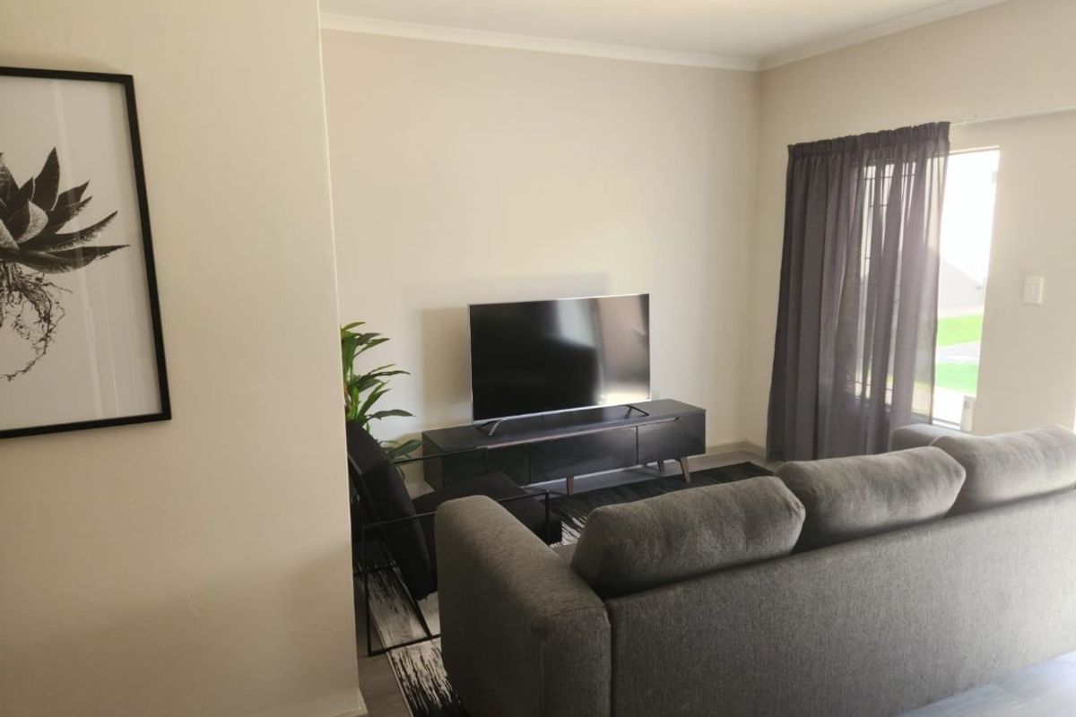 A bright and neutral living room featuring a sliding door with curtain tracks, providing access to the exterior.