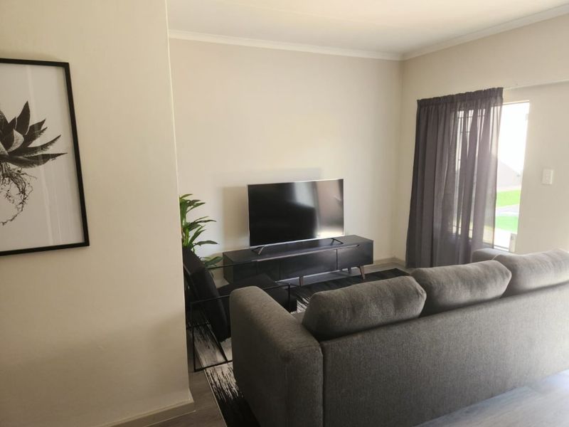 A bright and neutral living room featuring a sliding door with curtain tracks, providing access to the exterior.