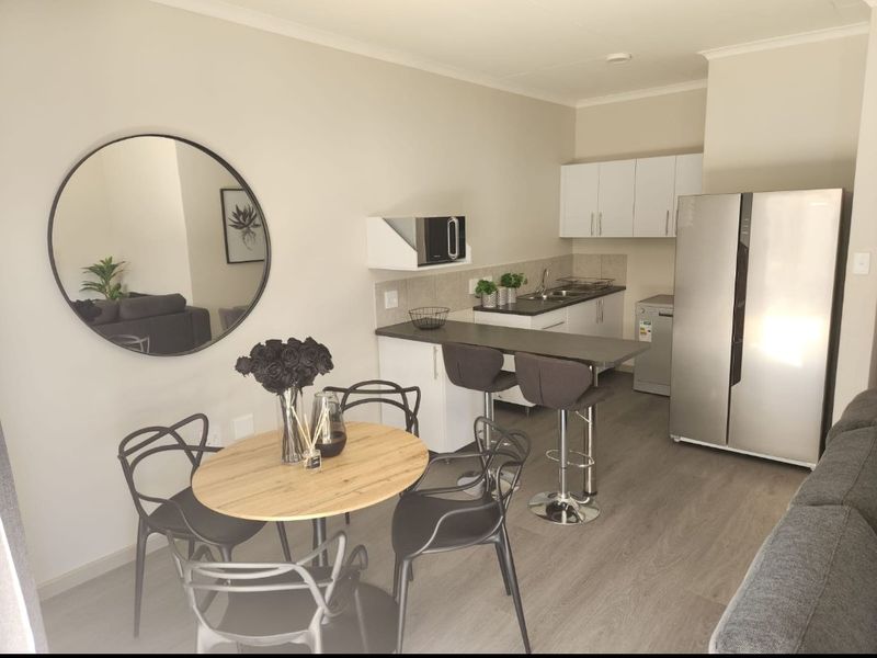 Open plan kitchen and dining area featuring modern cabinetry, laminate countertops, a breakfast bar, and durable laminate flooring.