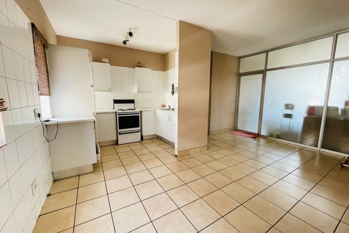 A functional kitchen area featuring tiled flooring, built-in cabinetry, and a freestanding stove, adjacent to a glass-partitioned space.