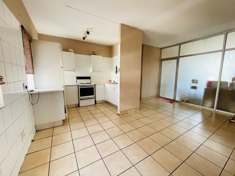 A functional kitchen area featuring tiled flooring, built-in cabinetry, and a freestanding stove, adjacent to a glass-partitioned space.