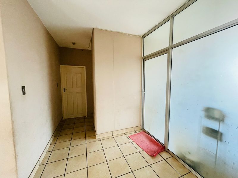 A functional entrance area featuring tiled flooring and an aluminium-framed glass partition, providing a clean and neutral space for a welcoming foyer.