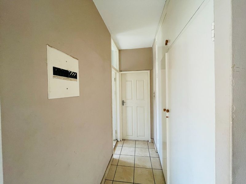 A functional hallway featuring tiled flooring, built-in storage cupboards, and a wall-mounted electrical distribution board.