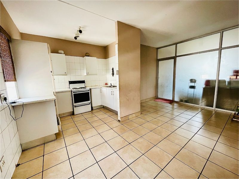Open plan kitchen and living area featuring tiled flooring, built-in cabinetry, and a large aluminium framed glass partition.