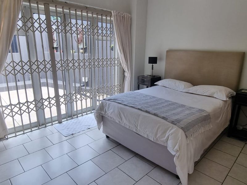 A bedroom featuring tiled flooring and a sliding glass door with a fitted metal security gate, providing direct access to an outdoor area.