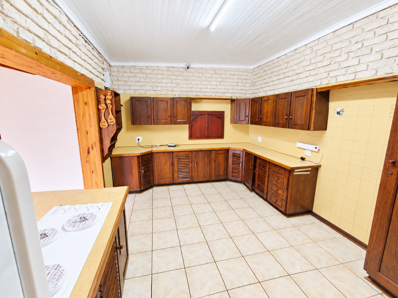 Spacious kitchen featuring extensive wooden cabinetry, laminate countertops, ceramic wall tiling, and a classic tongue and groove ceiling.