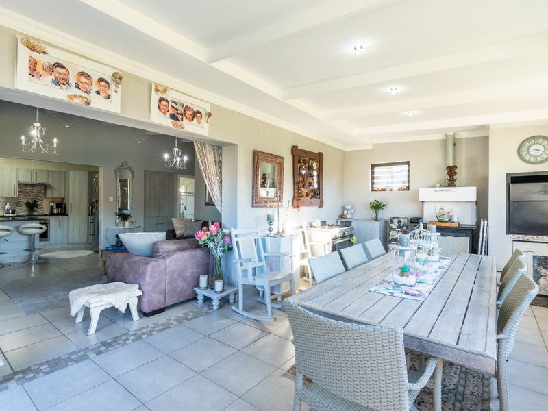 Spacious open-plan living and dining area featuring tiled floors, recessed lighting, a built-in fireplace, and a connected kitchen with modern cabinetry.