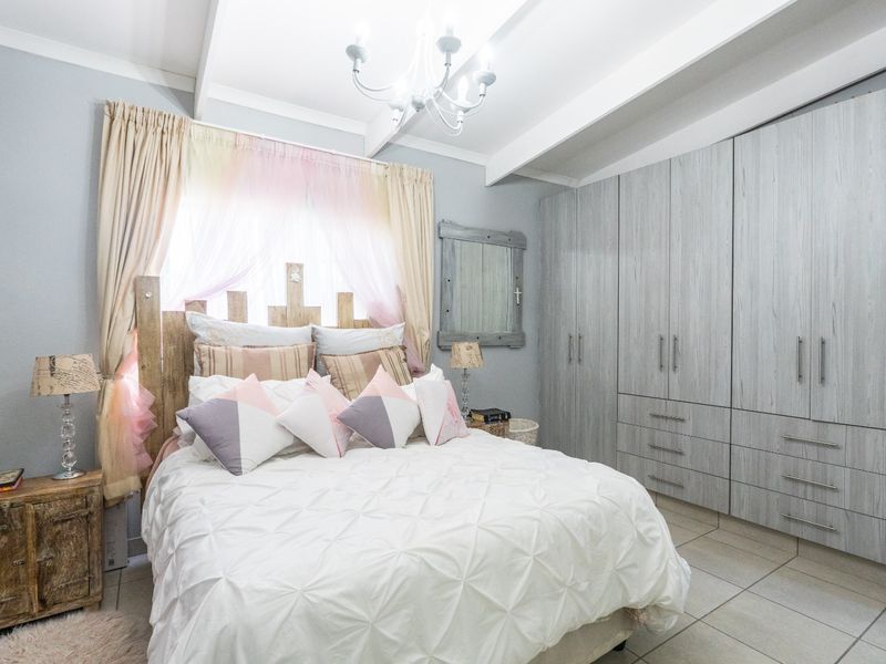 A well-maintained bedroom featuring built-in cupboards, tiled flooring, and exposed ceiling beams, providing a functional and comfortable living space.