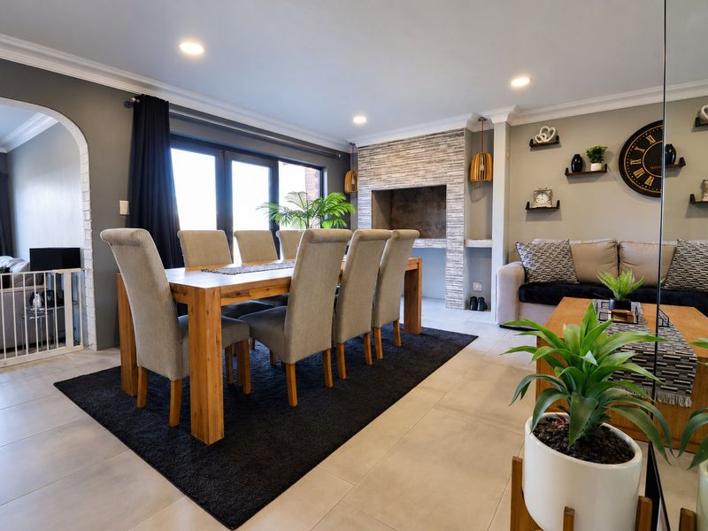 Spacious open-plan living and dining area featuring a built-in fireplace with stone cladding, tiled floors, and direct access to the outdoors via sliding doors.