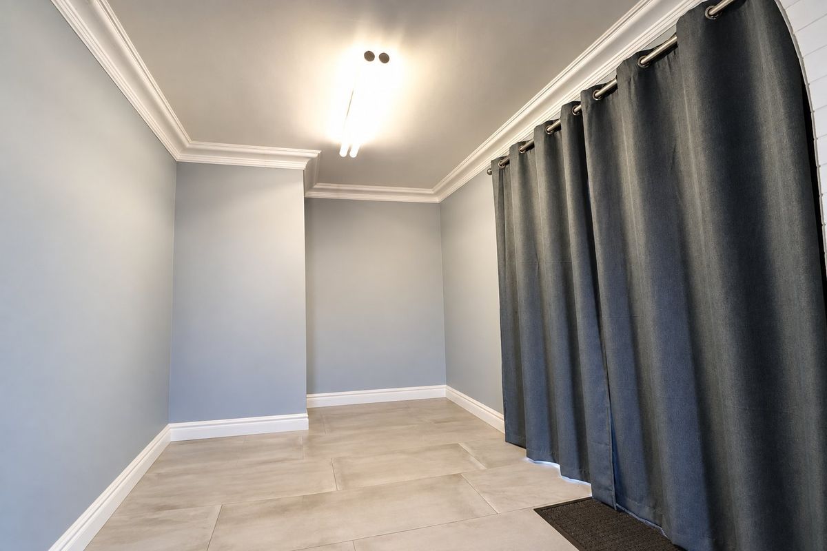 A clean, empty bedroom featuring neutral grey walls, crown molding, and modern tile flooring, providing a versatile space ready for personalization.