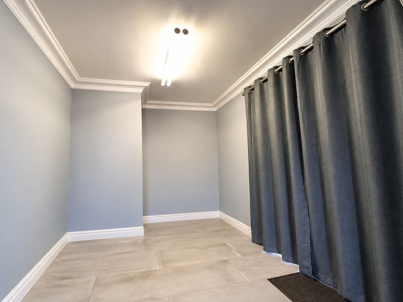 A clean, empty bedroom featuring neutral grey walls, crown molding, and modern tile flooring, providing a versatile space ready for personalization.