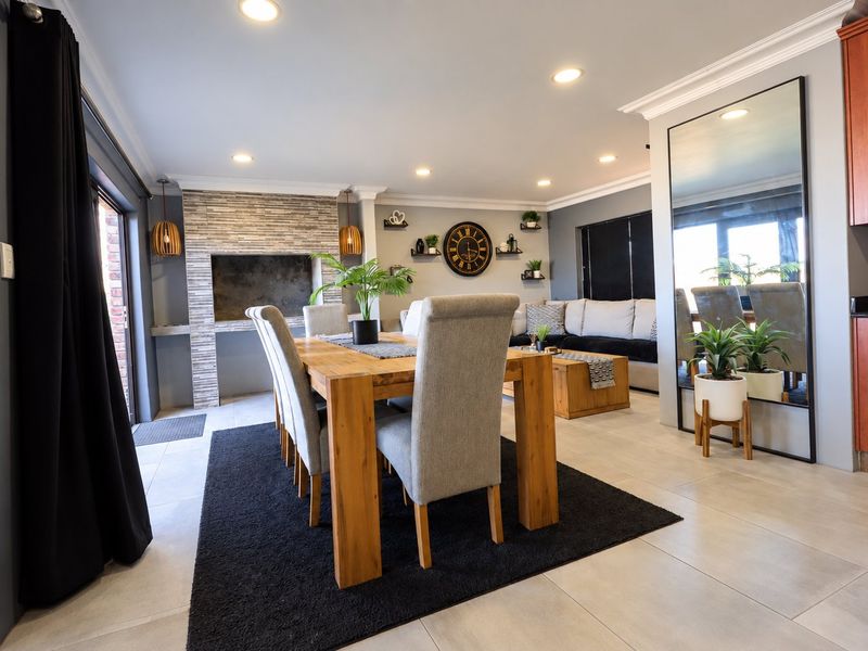Spacious open-plan living and dining area featuring a stone-clad fireplace, tiled flooring, and recessed lighting, creating a warm and inviting atmosphere.