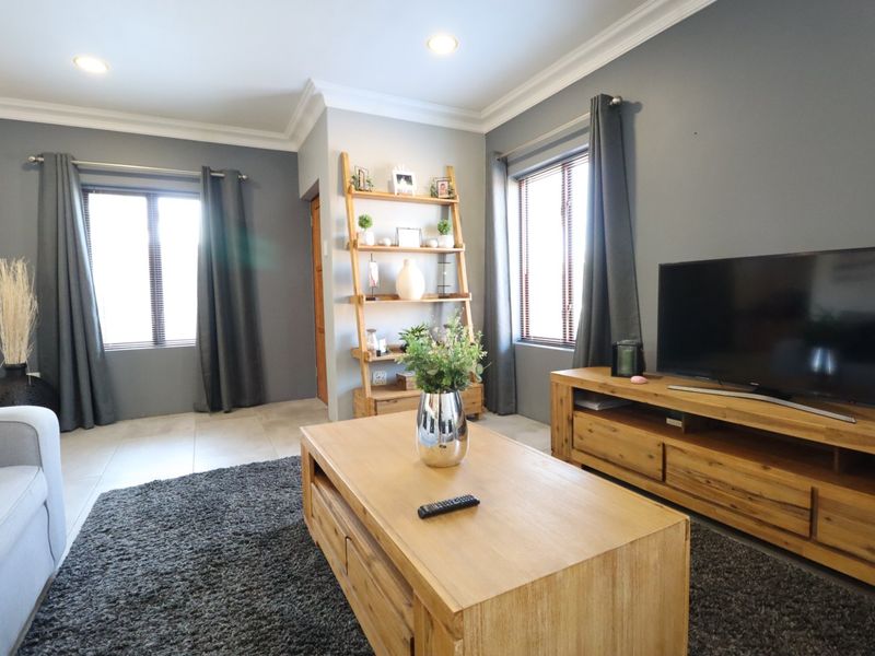 A well-maintained living room featuring tiled flooring, recessed downlighting, and crown molding, creating a comfortable and inviting atmosphere.
