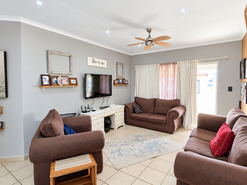 A well-maintained living room featuring neutral tiled flooring, a ceiling fan, recessed lighting, and direct access to the exterior through a sliding glass door.