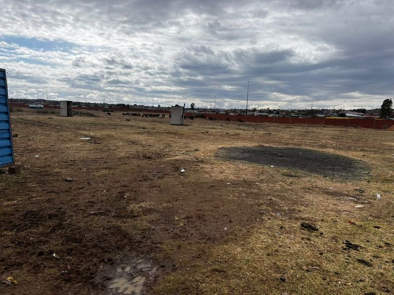 A large, undeveloped plot of land featuring a perimeter wall and open, unlandscaped ground.