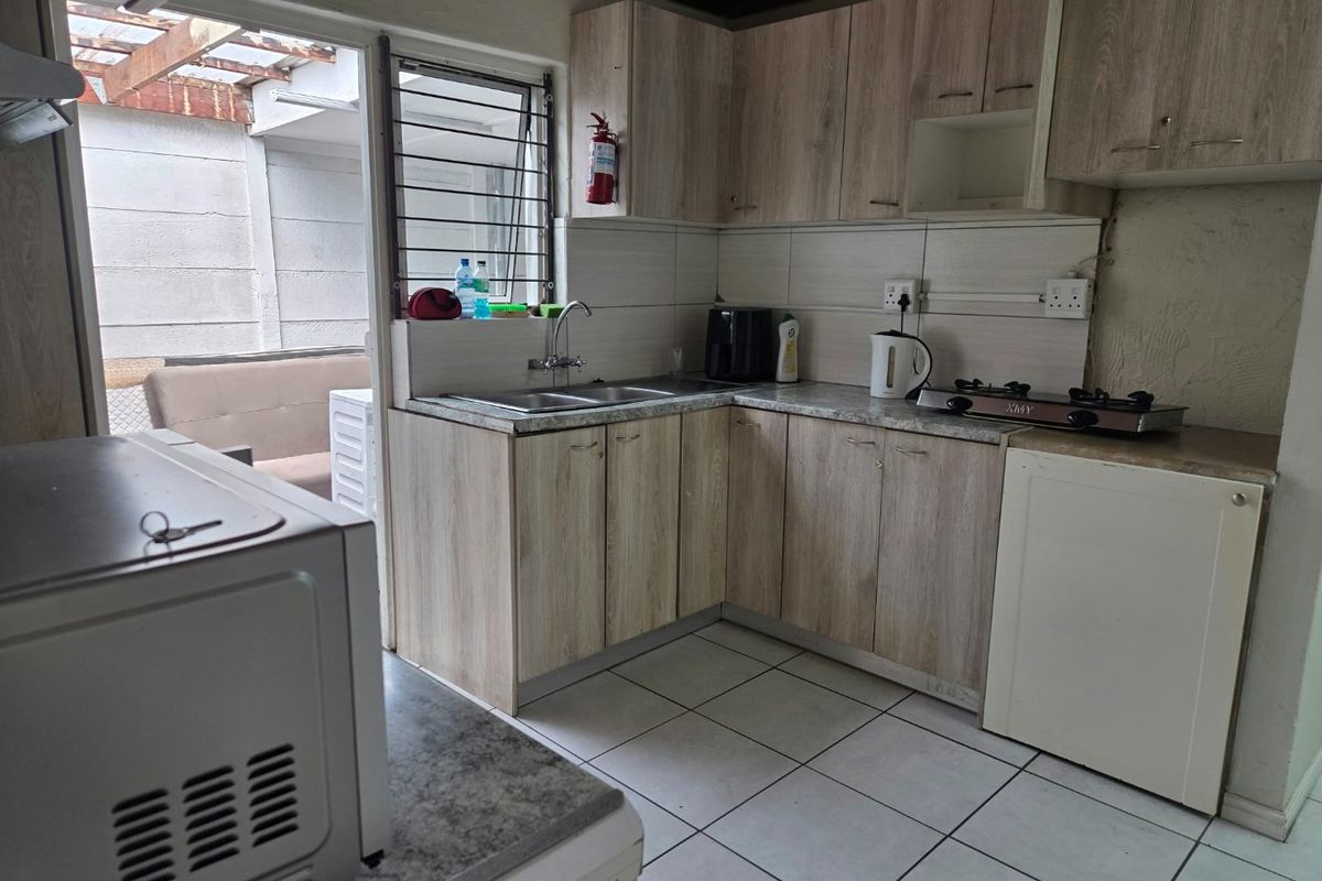 Functional kitchen featuring laminate cabinetry, gas hob, double basin sink, and tiled flooring with direct access to an outdoor patio area.