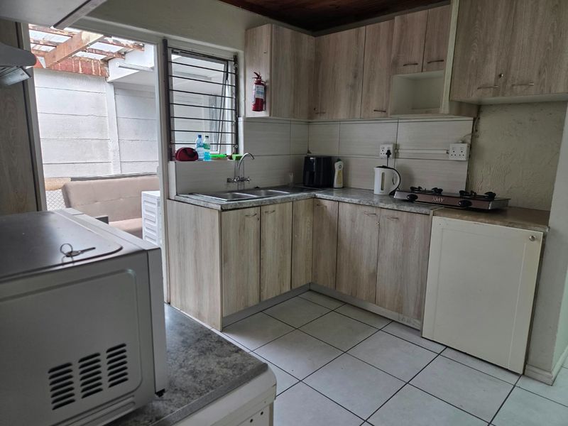 Functional kitchen featuring laminate cabinetry, gas hob, double basin sink, and tiled flooring with direct access to an outdoor patio area.