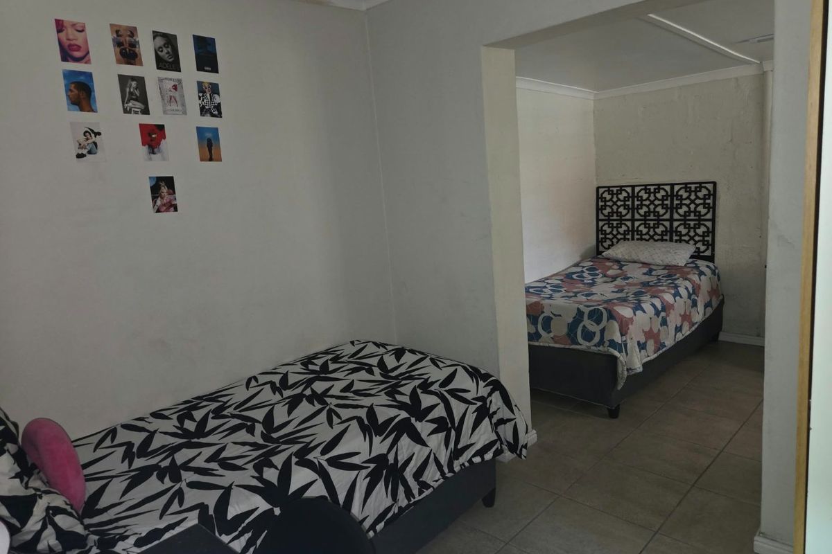 A bedroom featuring tiled flooring and coved ceilings, showing signs of wear including visible water staining on the ceiling.