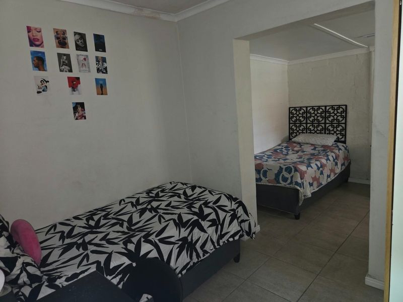 A bedroom featuring tiled flooring and coved ceilings, showing signs of wear including visible water staining on the ceiling.
