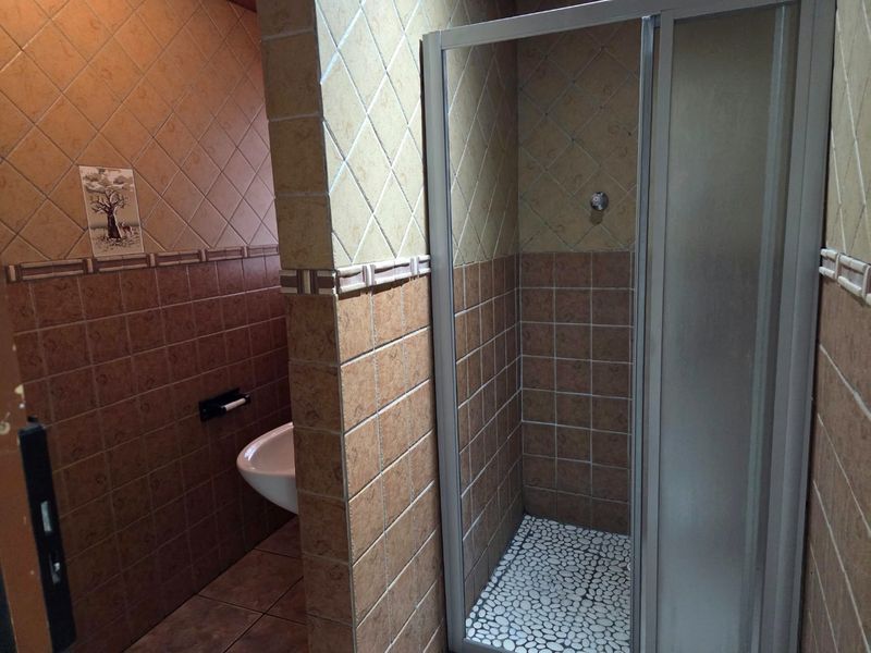 A functional bathroom featuring a shower enclosure with a pebble-style floor and tiled wall finishes.