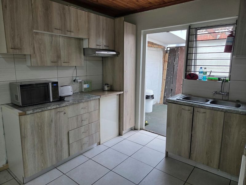 Functional kitchen featuring wood-look laminate cabinetry, tiled flooring, timber ceiling, and direct access to an outdoor area.