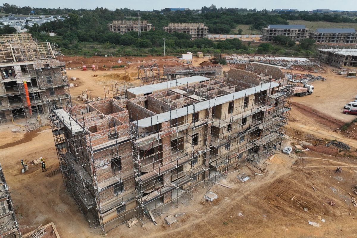 Aerial view of an apartment complex currently under construction, showing the structural brickwork and scaffolding in place.