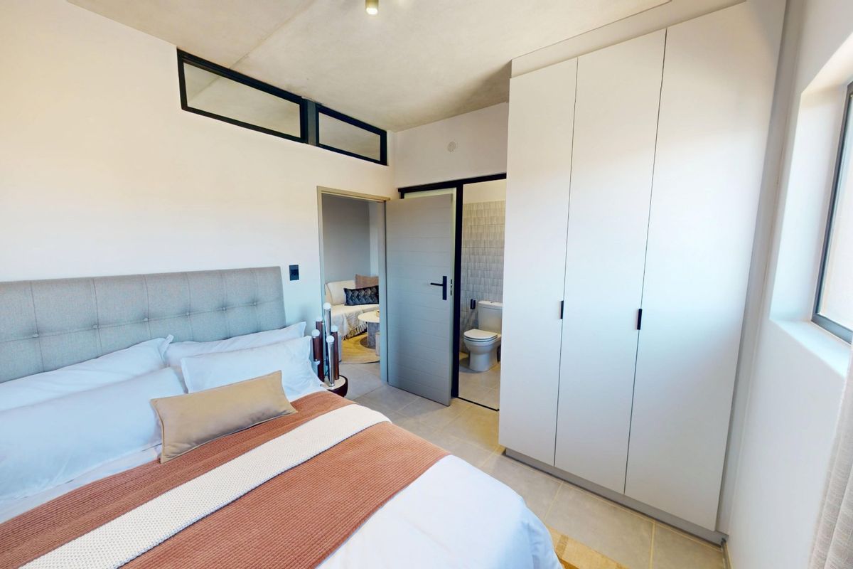 Modern bedroom featuring built-in cupboards, clerestory windows for natural light, and direct access to an en-suite bathroom.