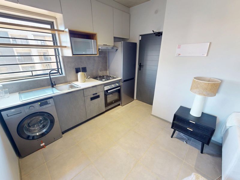Modern kitchen featuring built-in cabinetry, gas hob, oven, extractor fan, integrated microwave, and tiled flooring with a window providing natural light.