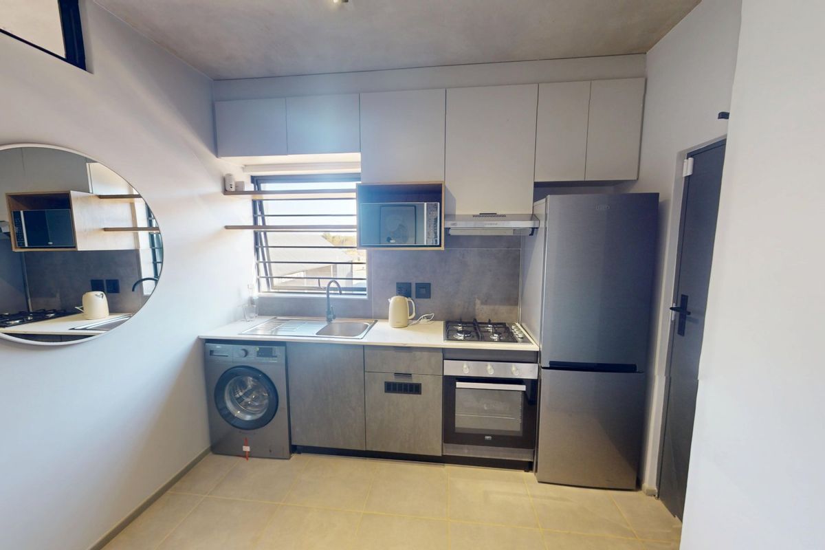 Modern compact kitchen featuring built-in cabinetry, stainless steel sink, gas hob, electric oven, extractor fan, and tiled flooring.