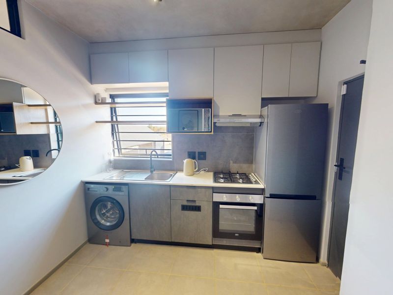 Modern compact kitchen featuring built-in cabinetry, stainless steel sink, gas hob, electric oven, extractor fan, and tiled flooring.