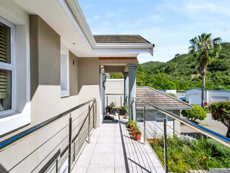 A well-maintained balcony featuring tiled flooring, stainless steel balustrades, and decorative columns, offering a pleasant outdoor space with views of the surrounding landscape.