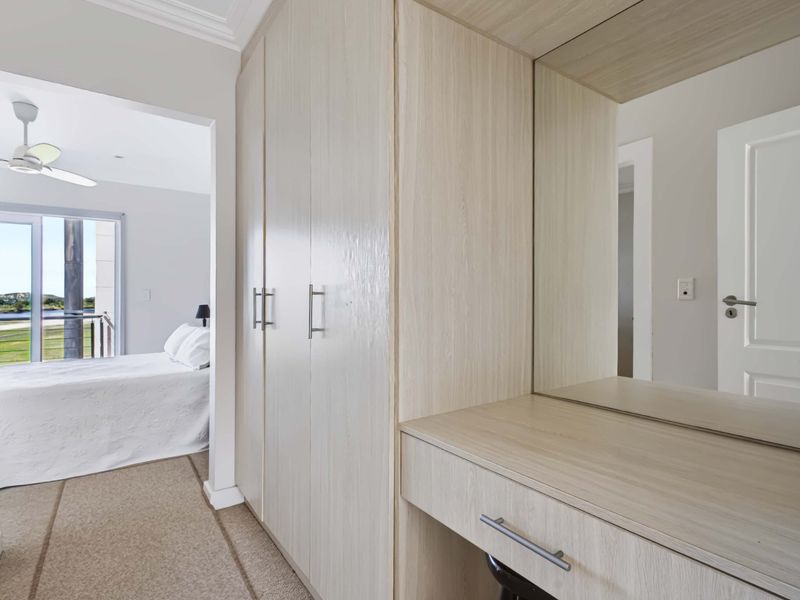Bedroom featuring built-in cupboards with an integrated vanity and mirror, leading to an adjoining space with access to a balcony.