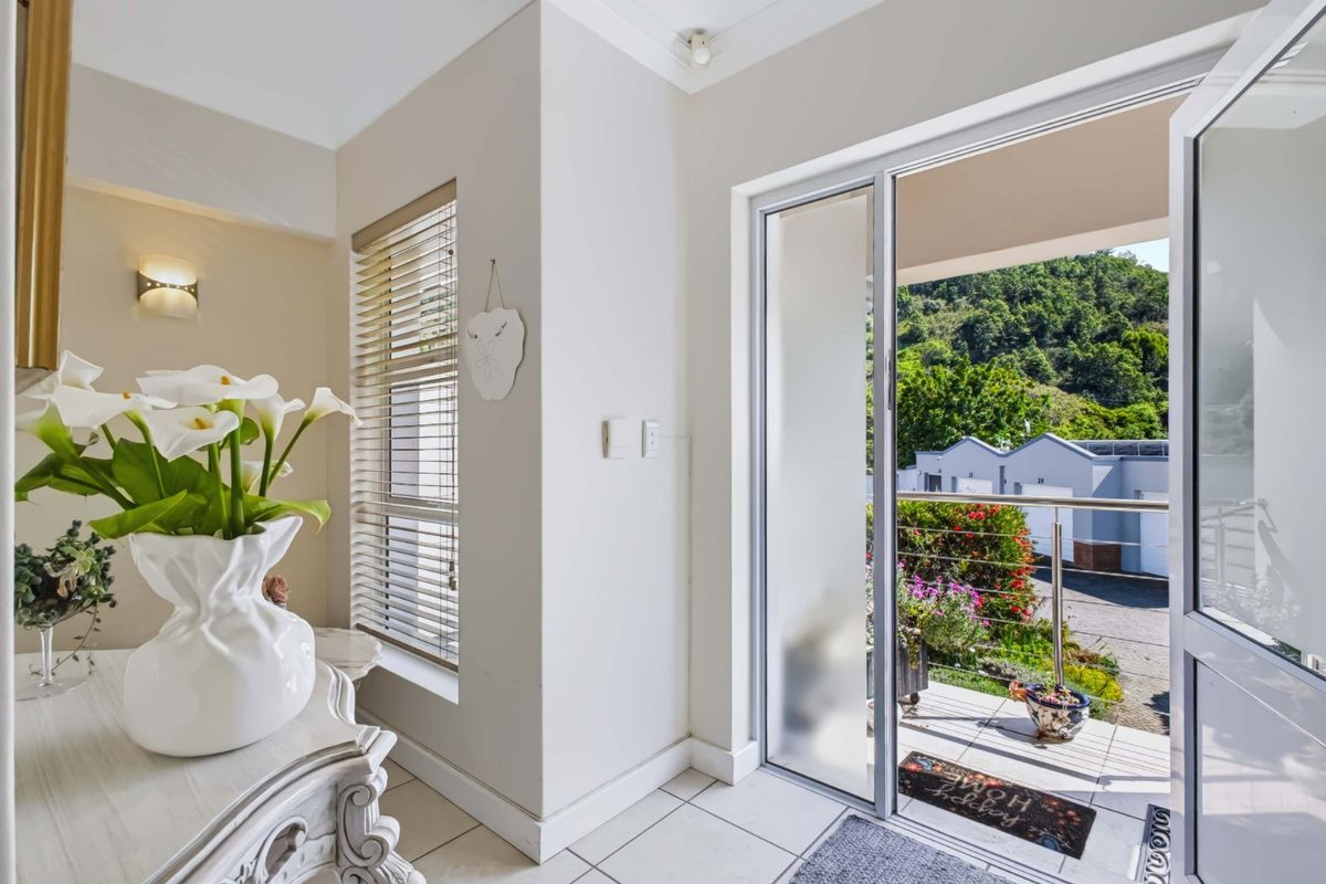 A bright living area featuring tiled flooring, a wall-mounted light fixture, and a sliding glass door providing access to an outdoor balcony.