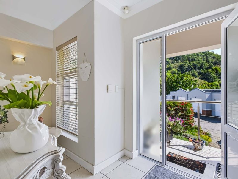 A bright living area featuring tiled flooring, a wall-mounted light fixture, and a sliding glass door providing access to an outdoor balcony.