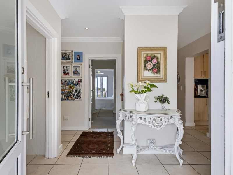 A bright and welcoming entrance hall featuring neutral wall tones, tiled flooring, and crown molding, providing a clear transition into the apartment's living spaces.