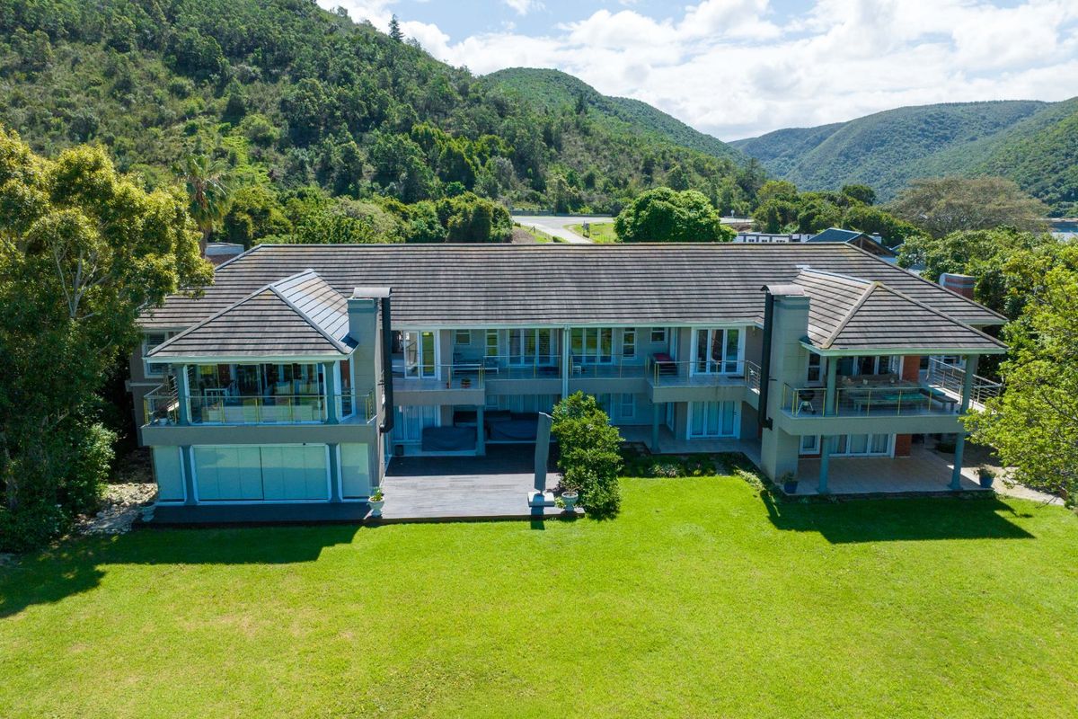Aerial view of a large multi-level residential property featuring a tiled roof, multiple balconies with glass balustrades, and a spacious rear lawn.