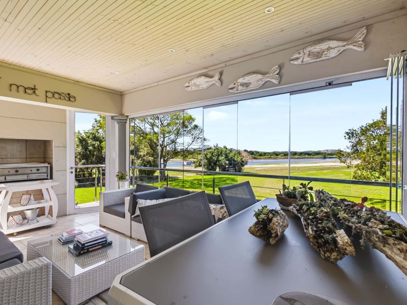 Covered patio featuring a built-in braai, glass stackable doors, and scenic views of the surrounding landscape.