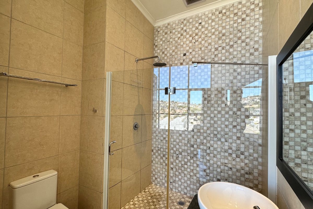 Modern bathroom featuring a walk-in shower with glass screen, mosaic tile accents, vessel sink, and neutral ceramic wall and floor tiling.